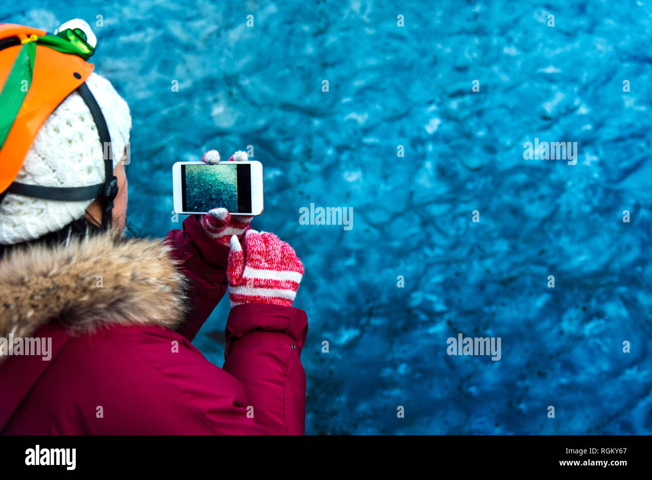 Woman taking photo of a blue ice cave in Iceland Stock Photo