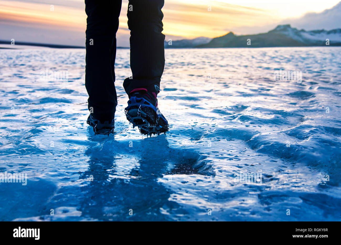Person walking on glacier ice surface wearing crampons low angle Stock Photo