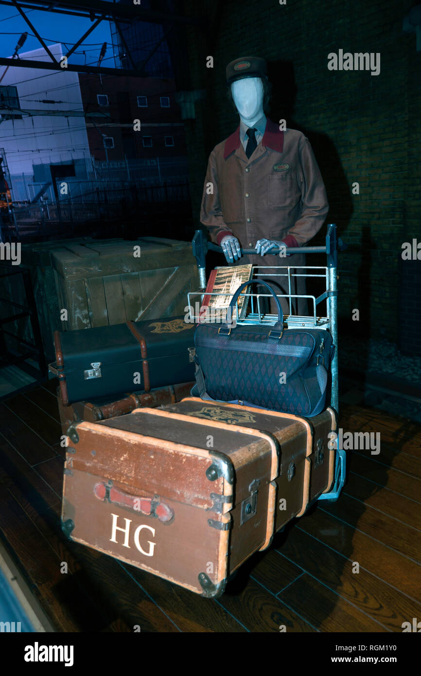 A Hogwarts Railway Porter pushes a trolley containing the luggage of Hermione Granger along platform 9 3/4 at Kings Cross, Warner Brothers Studio Tour Stock Photo