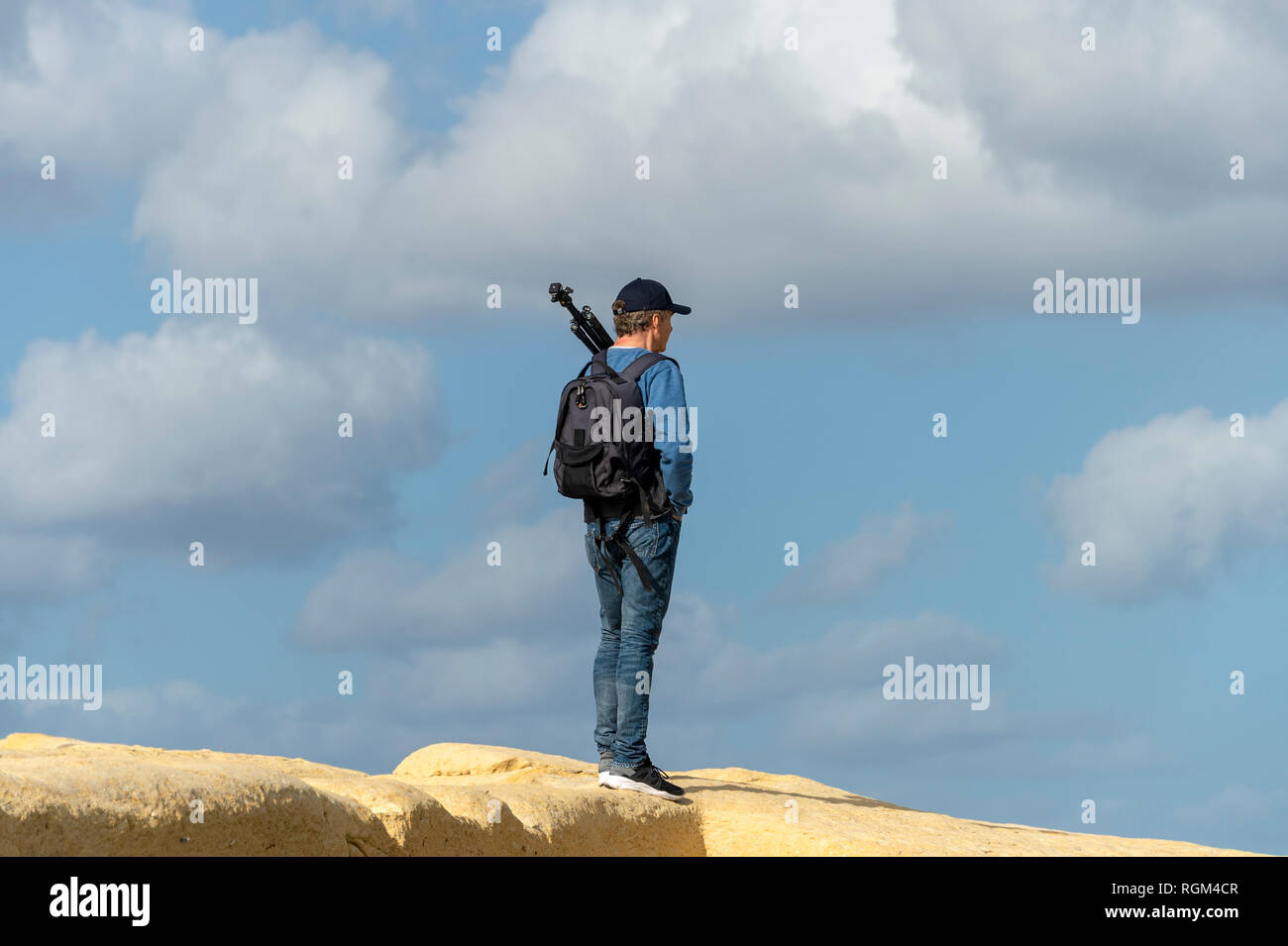 Man wearing a backpack and carrying a tripod standing on top of