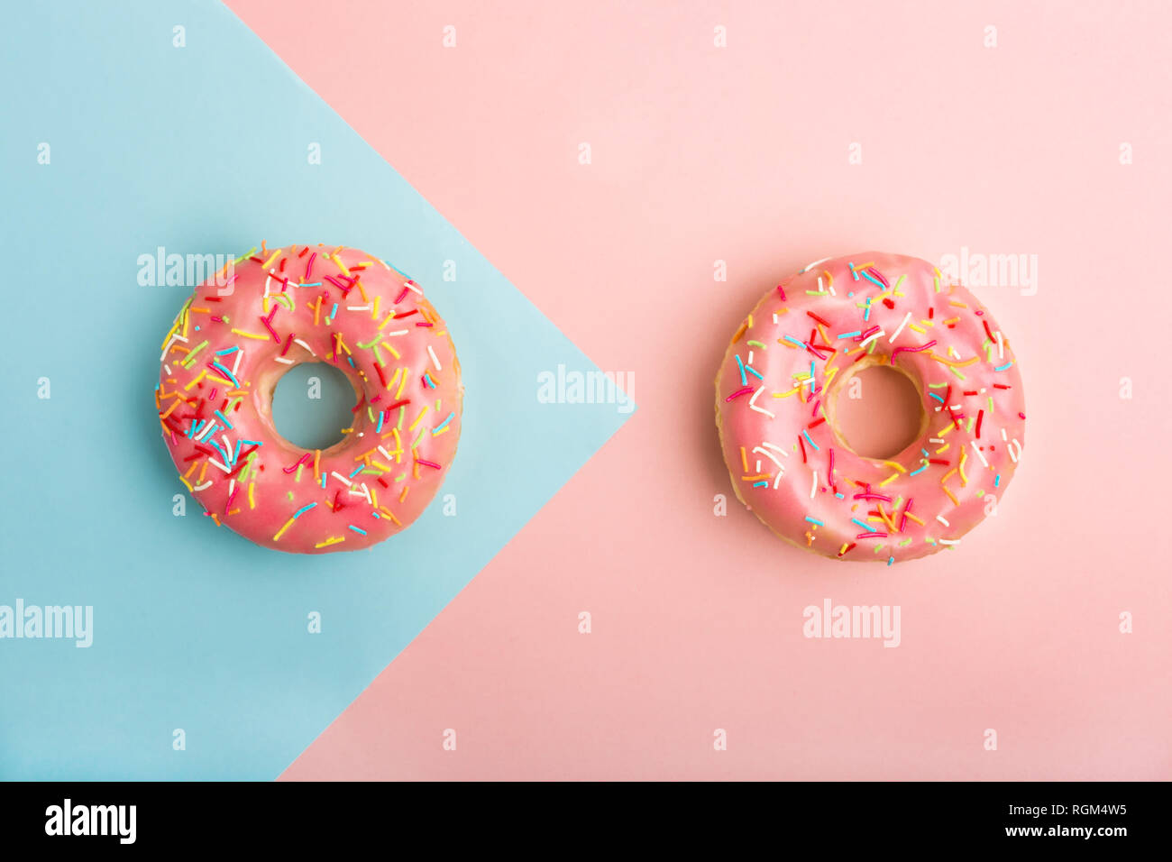 Two donuts decorated with sprinkles on colorful background. Coral and blue color background Stock Photo