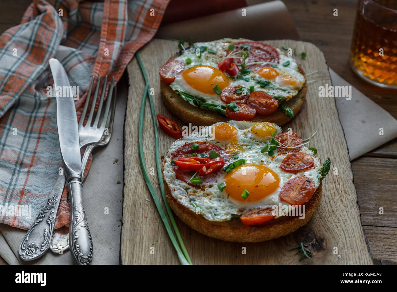 Toasts with eggs and tomatoes on cutting board Stock Photo