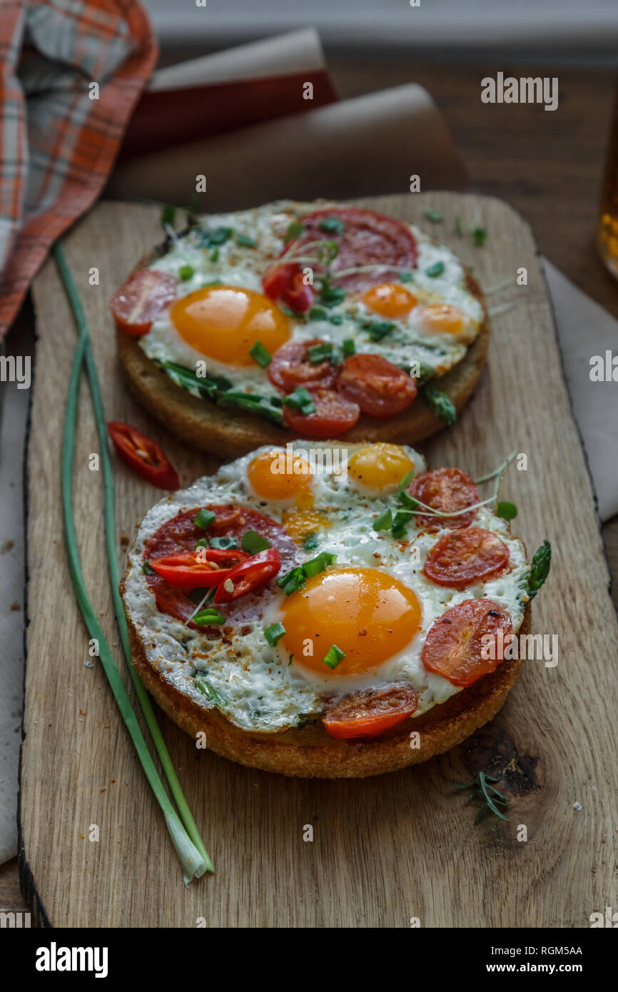 Toasts with eggs and tomatoes on cutting board Stock Photo