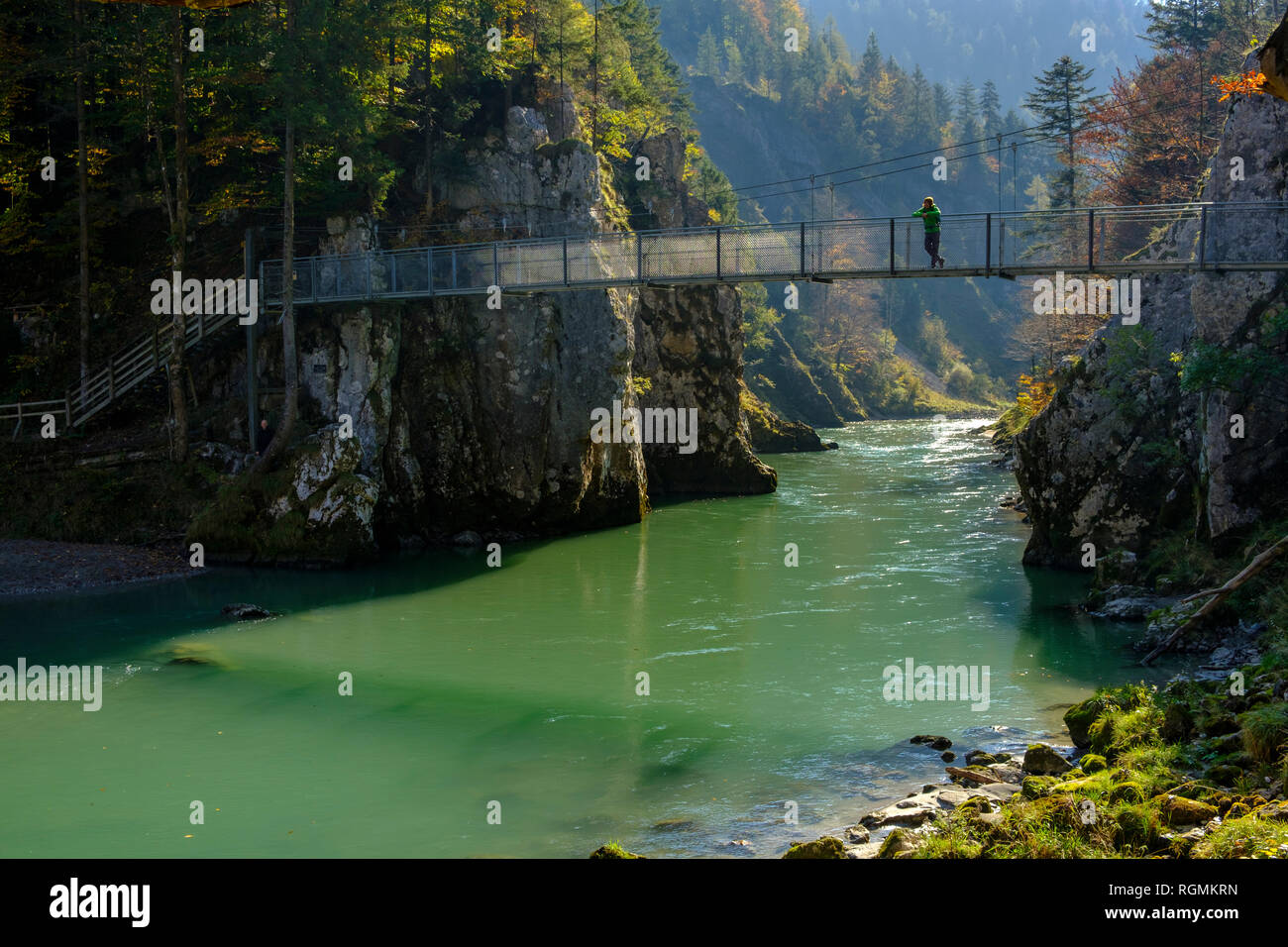 Austria, Tyrol, hiker on suspension bridge looking at Tiroler Ache in autumn Stock Photo