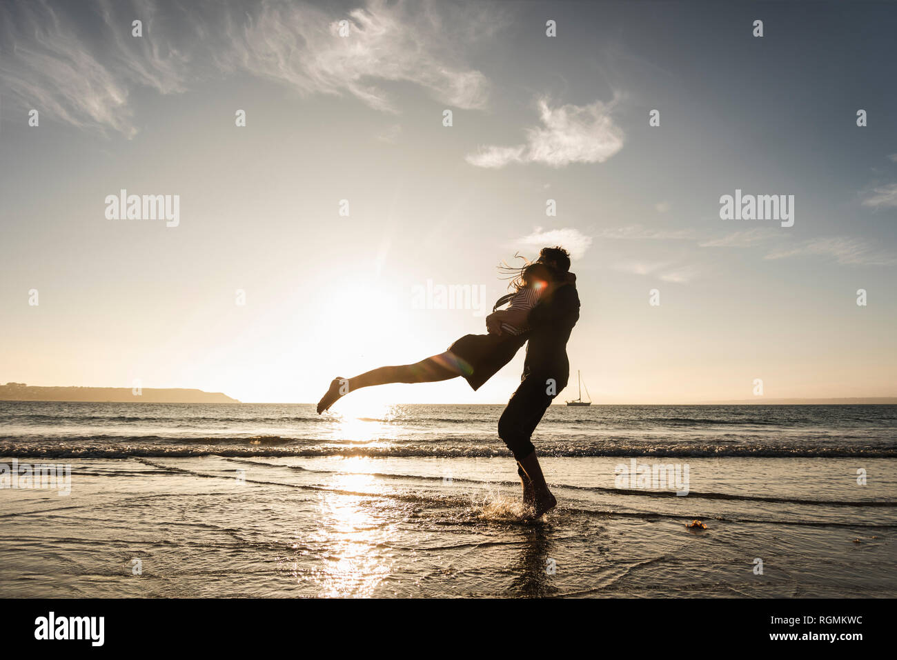 France, Brittany, happy young couple hugging on the beach at sunset Stock Photo