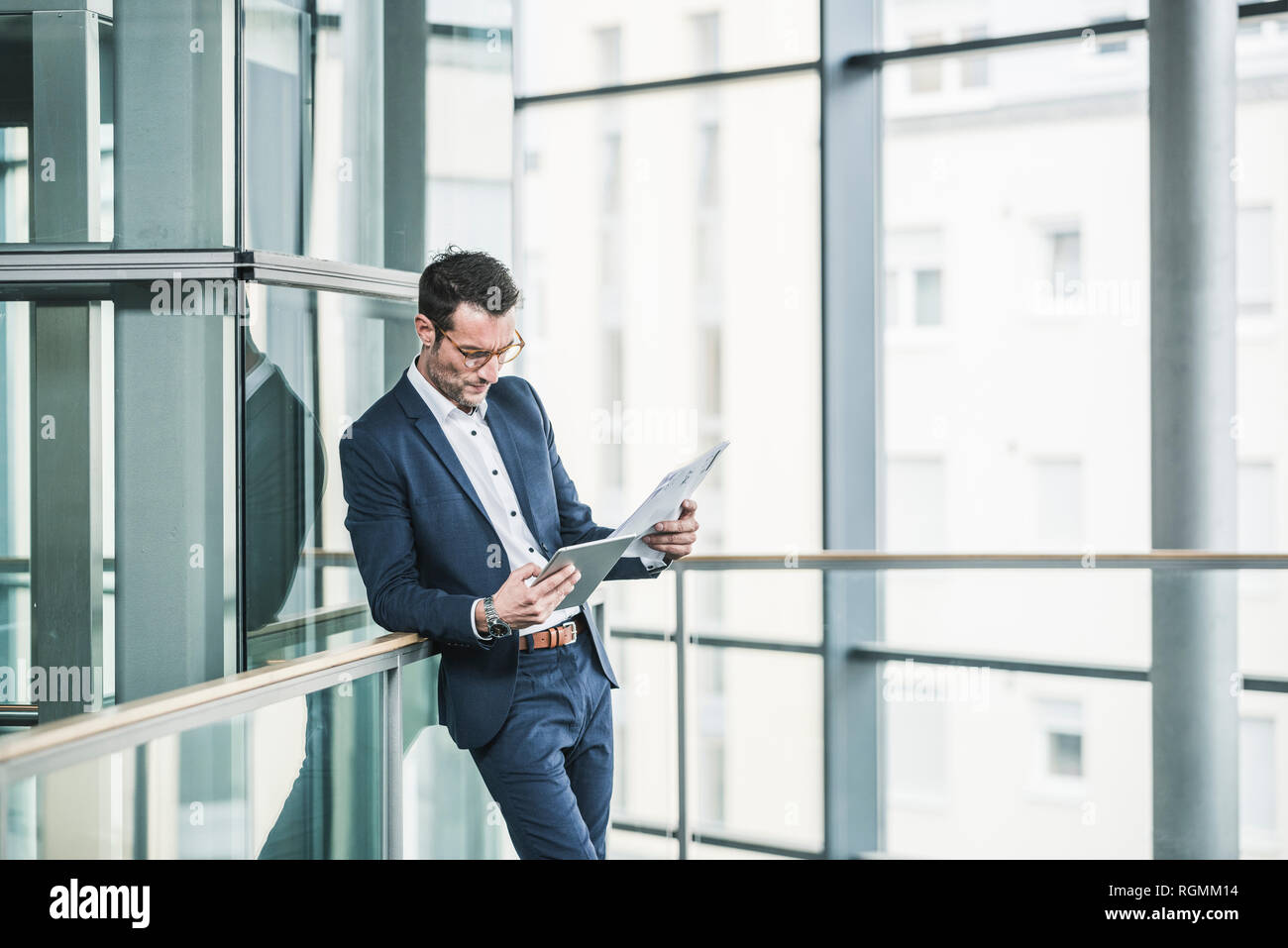 Businessman standing in office building, using digital tablet Stock Photo