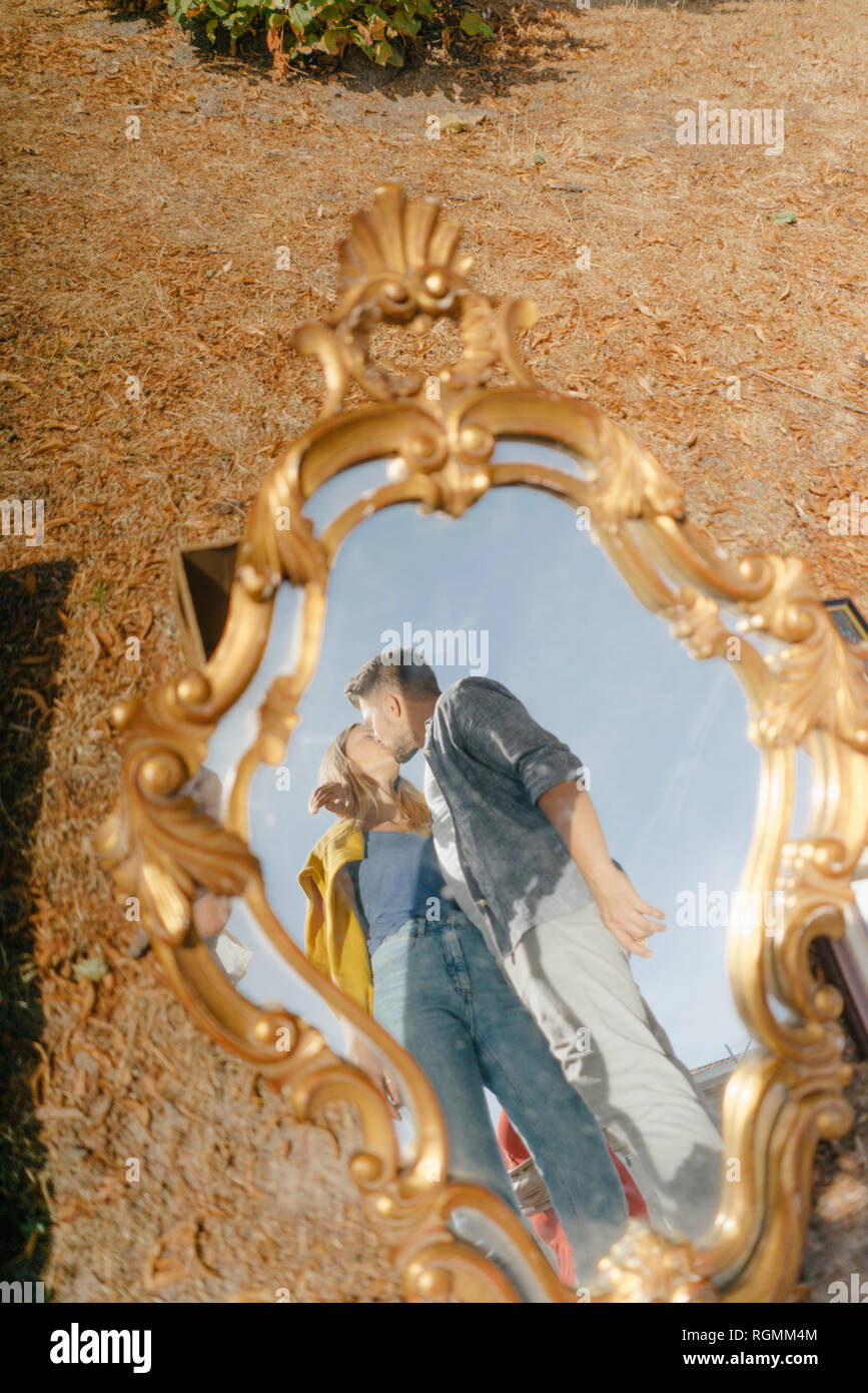 Affectionate young couple kissing reflected in vintage mirror Stock Photo