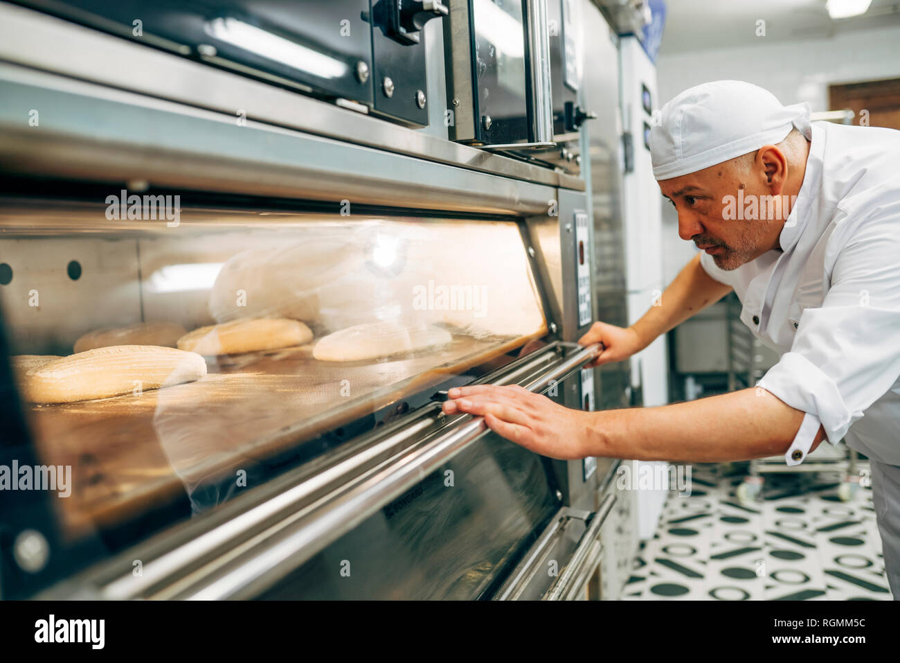 Working baker preparing the oven to make bread Stock Photo