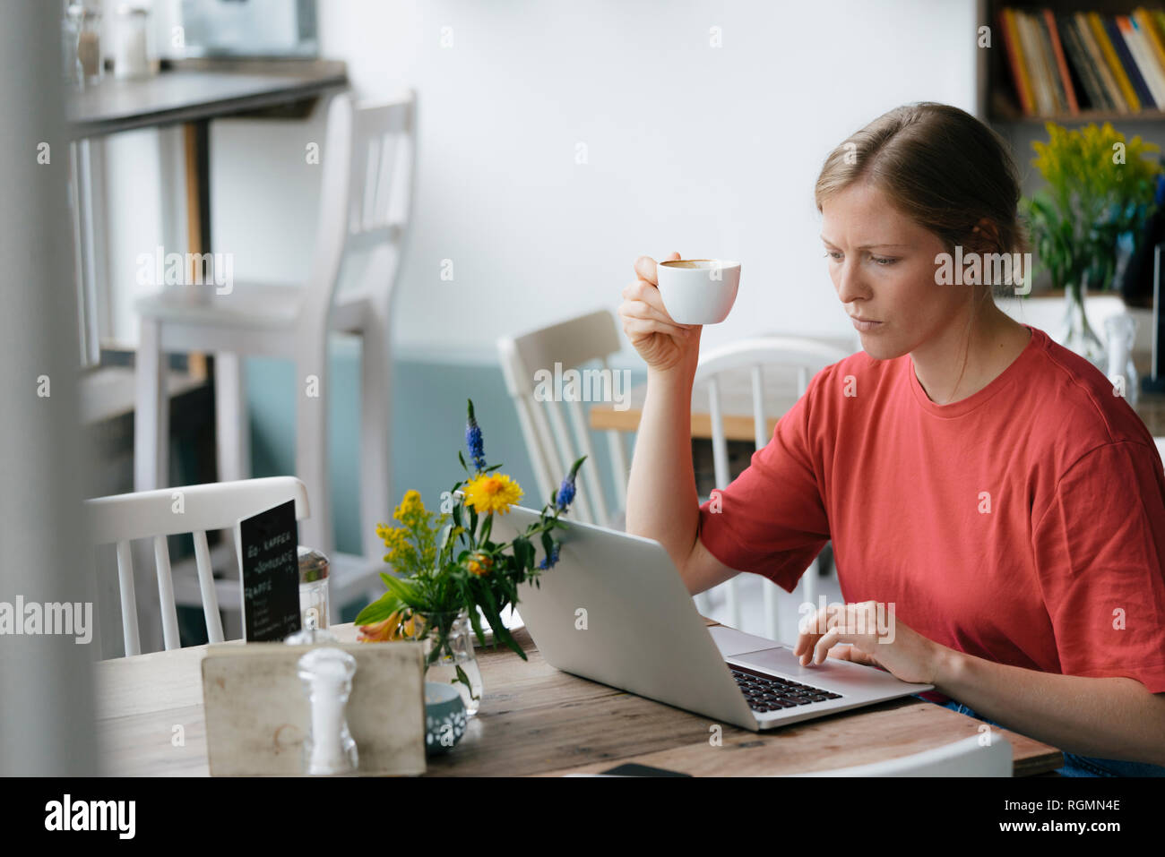 Young woman using laptop at table in a cafe Stock Photo