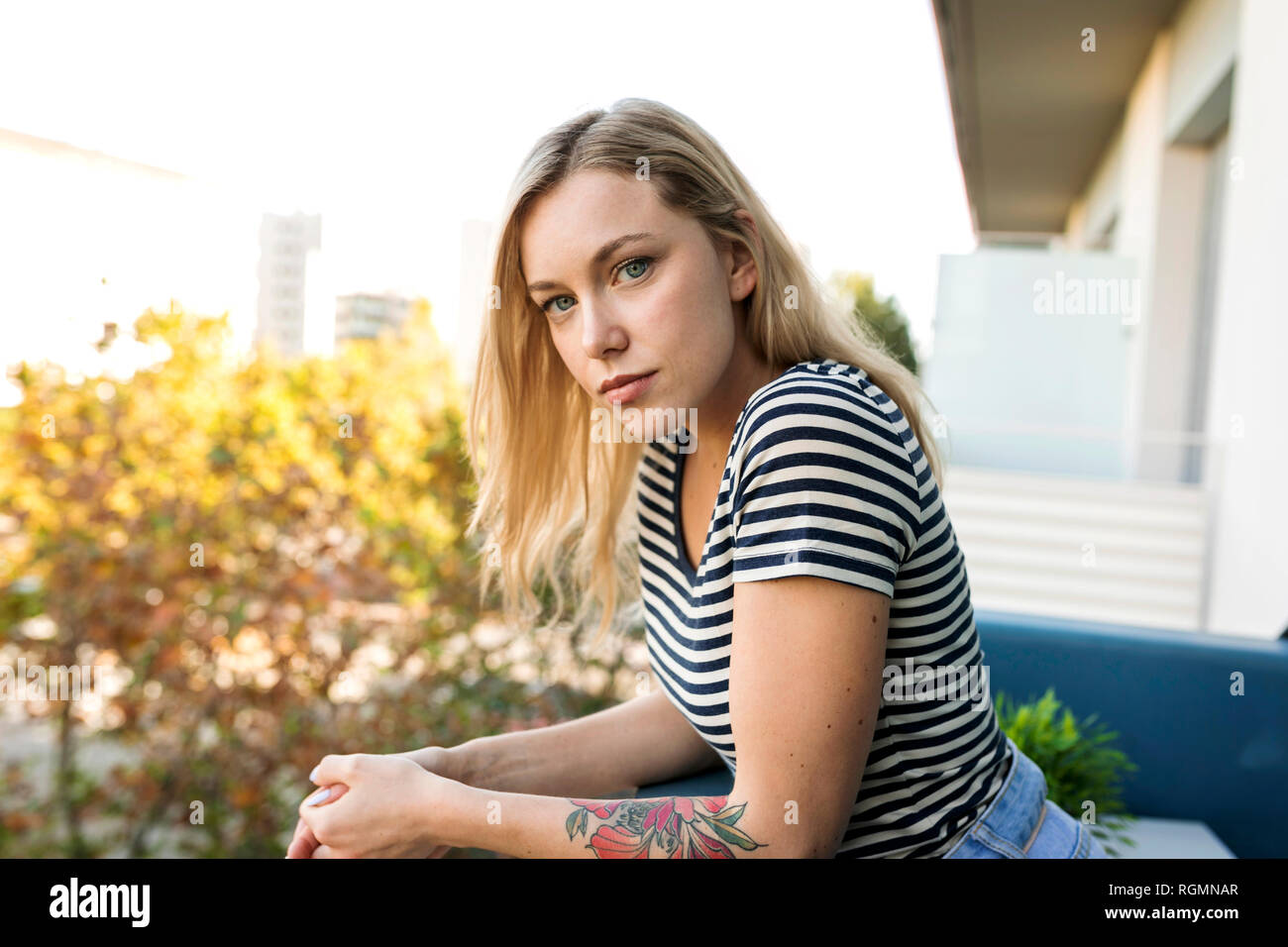 Portrait of blond young woman on balcony Stock Photo