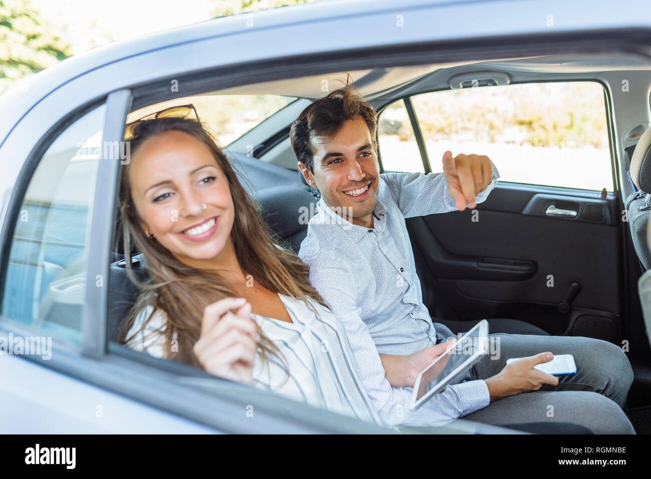 Smiling couple on back seat of a car looking out of window Stock Photo