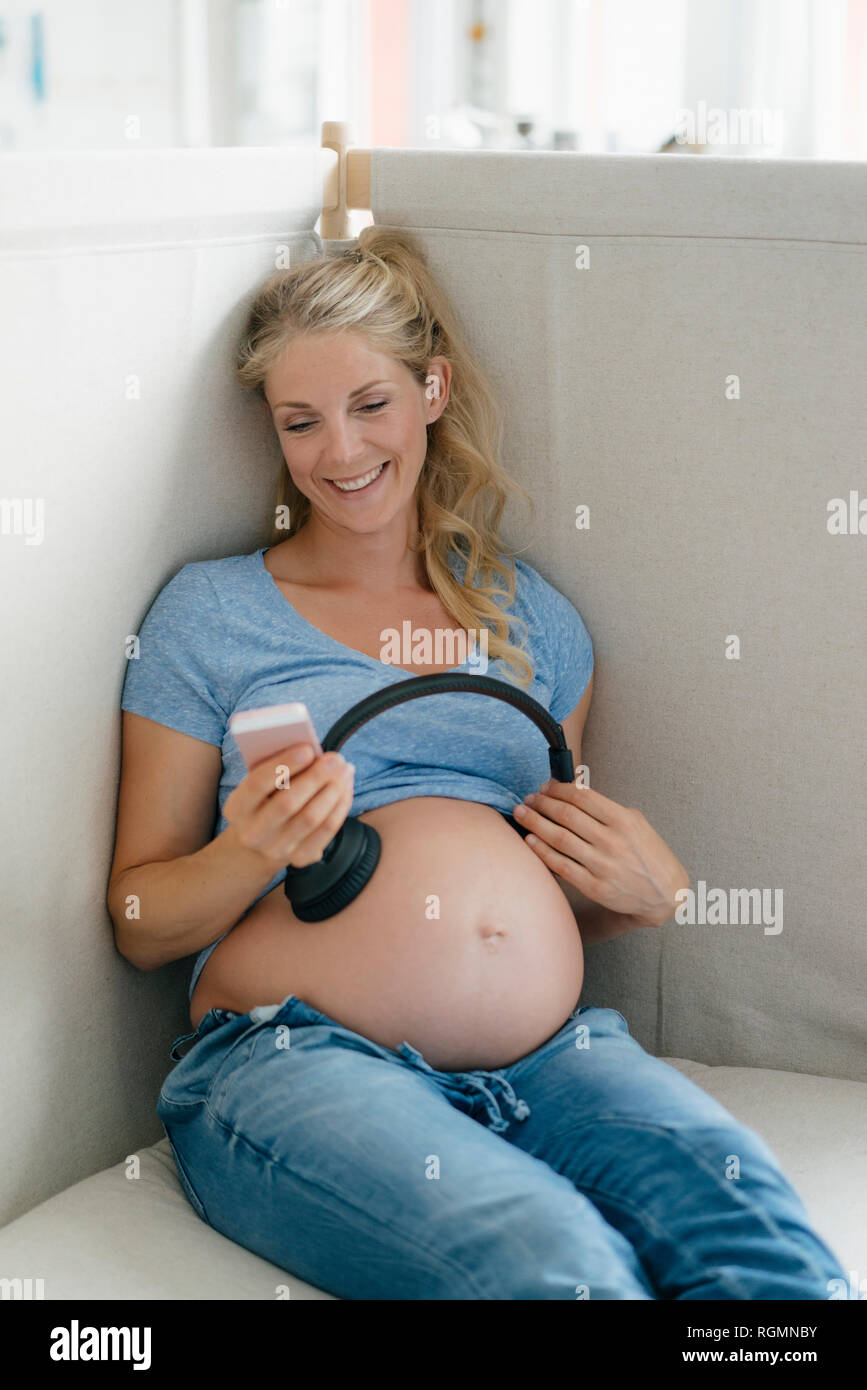 Smiling Pregnant Woman Putting Headphones On Her Belly In The Living Room  Stock Photo, Picture and Royalty Free Image. Image 44806928.