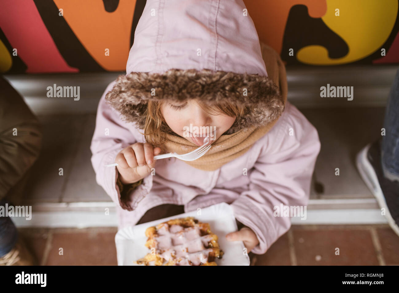 Belgium, little girl eating Belgian waffle in winter outdoors Stock