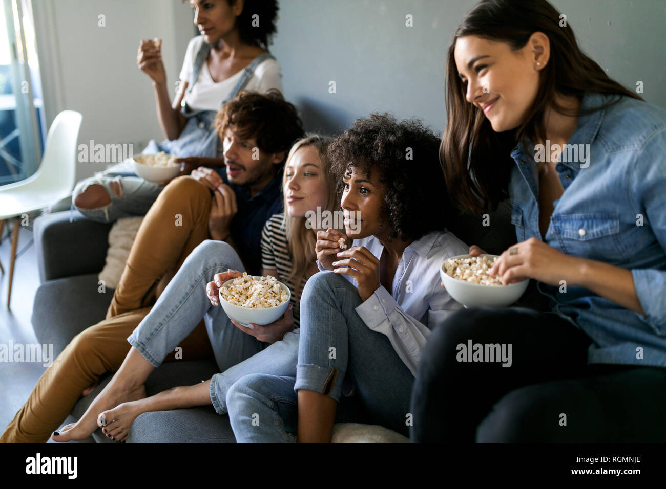 Friends sitting on couch watching tv Stock Photo