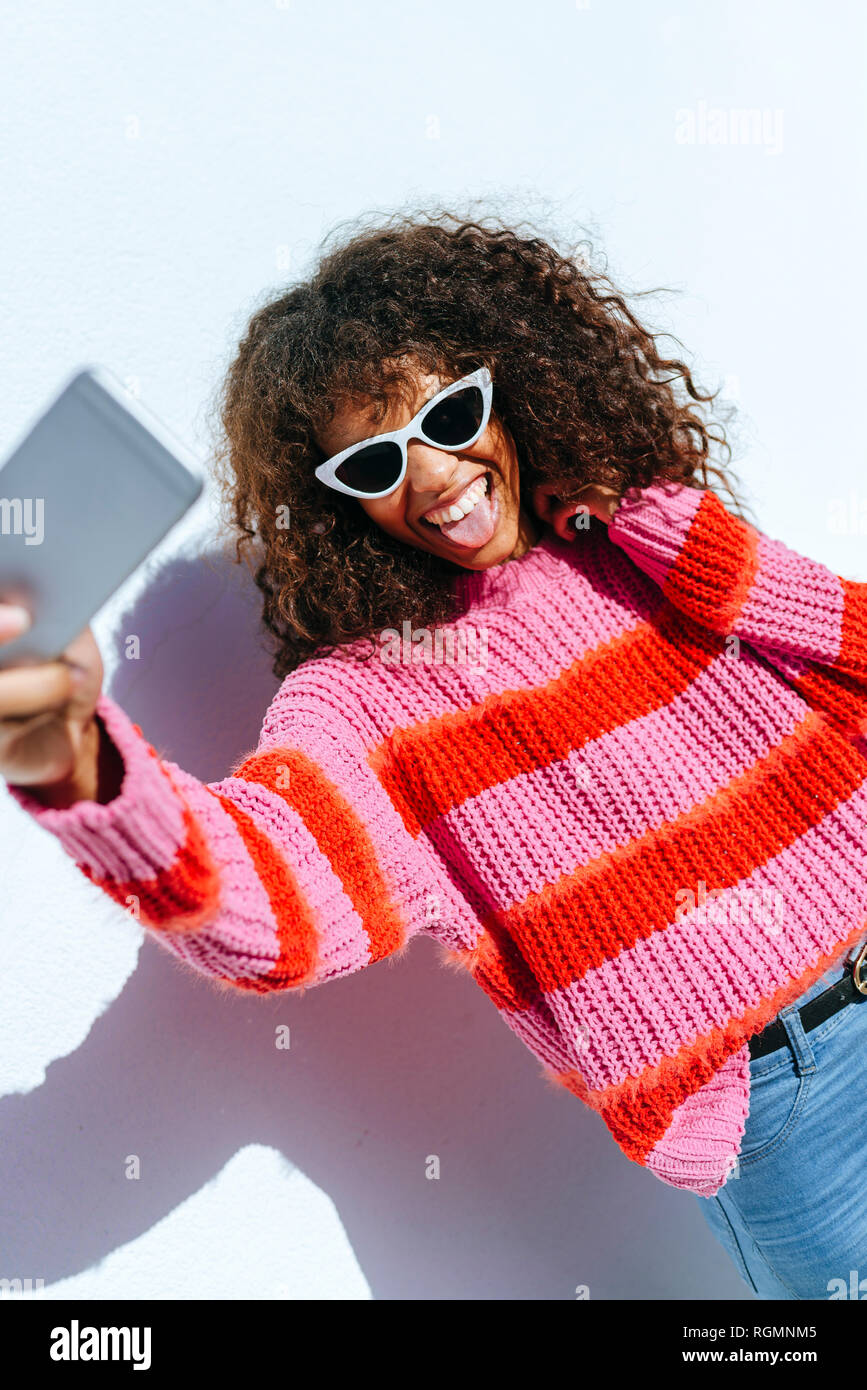 Portrait of young woman wearing sunglasses taking selfie with mobile phone Stock Photo