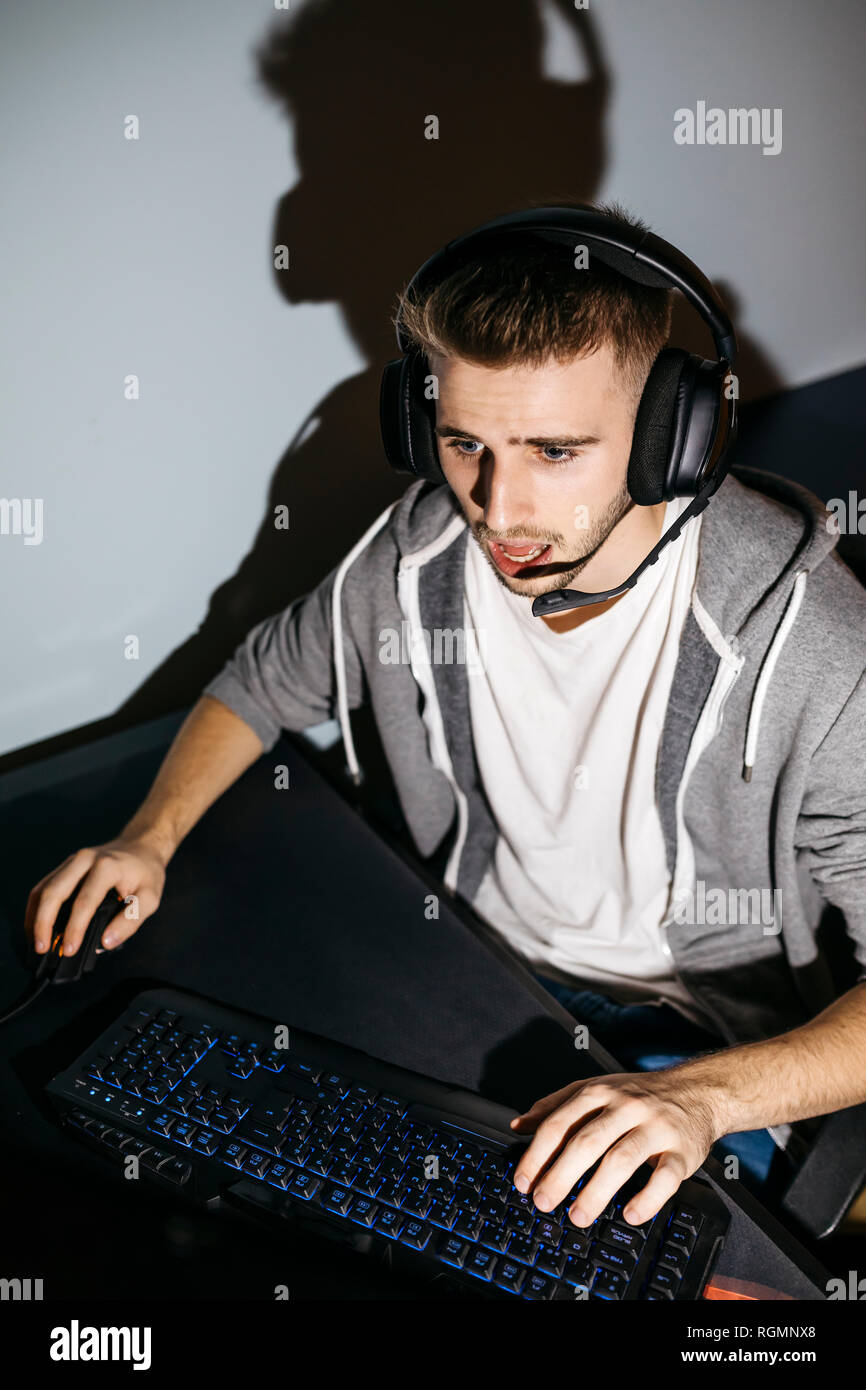 Young man sitting at his PC, playing computer games Stock Photo