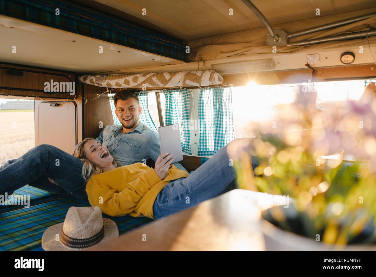 Happy young couple looking at tablet inside camper van Stock Photo