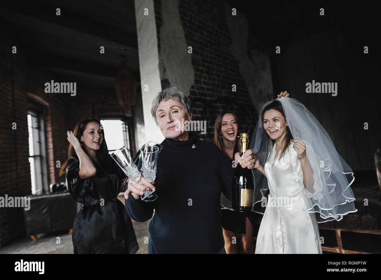 Bride's mother, bridesmaids and bride drinking champagne together Stock Photo
