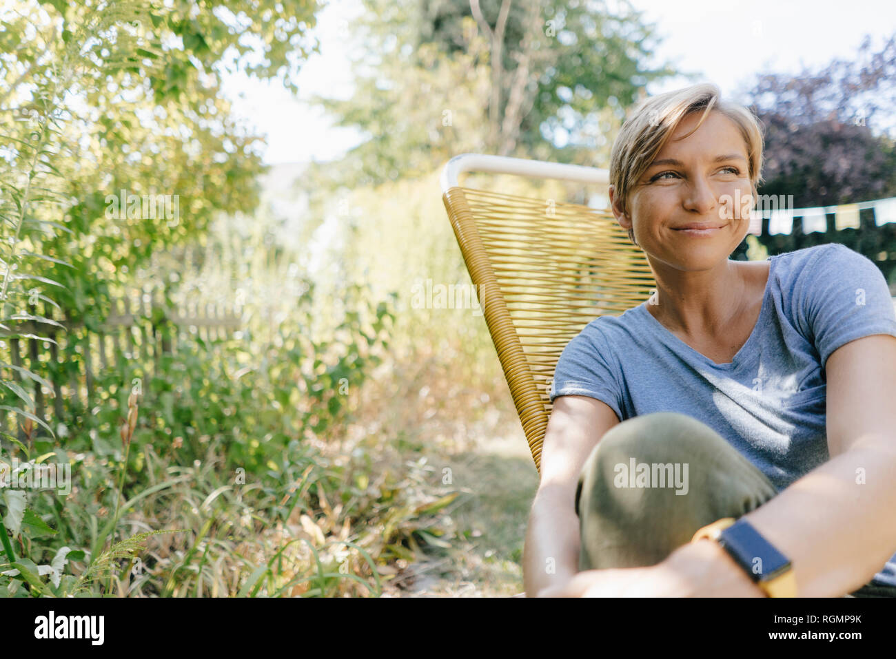 Woman sitting in garden on chair Stock Photo