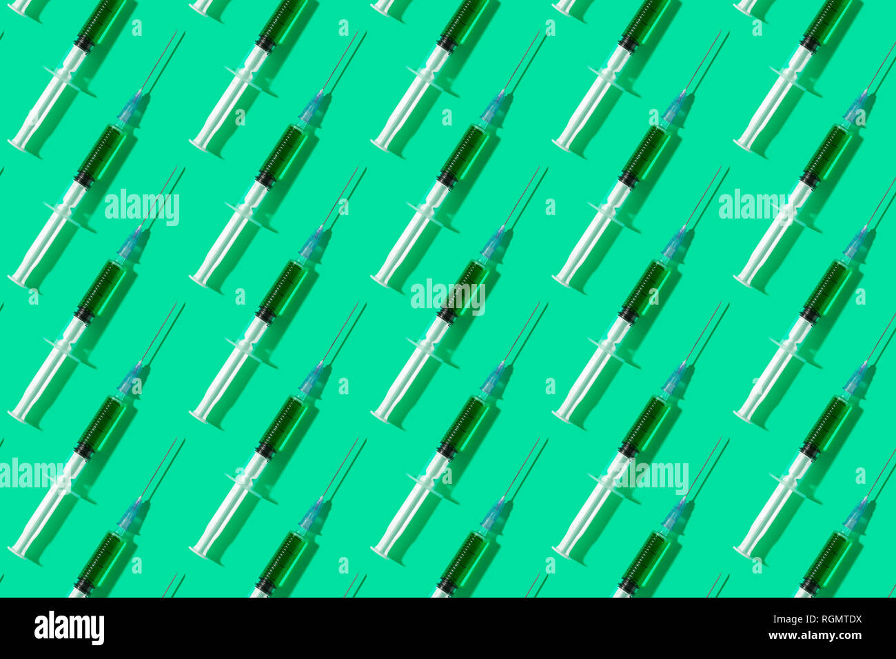 Multiple syringes organized in a pattern over green background Stock Photo