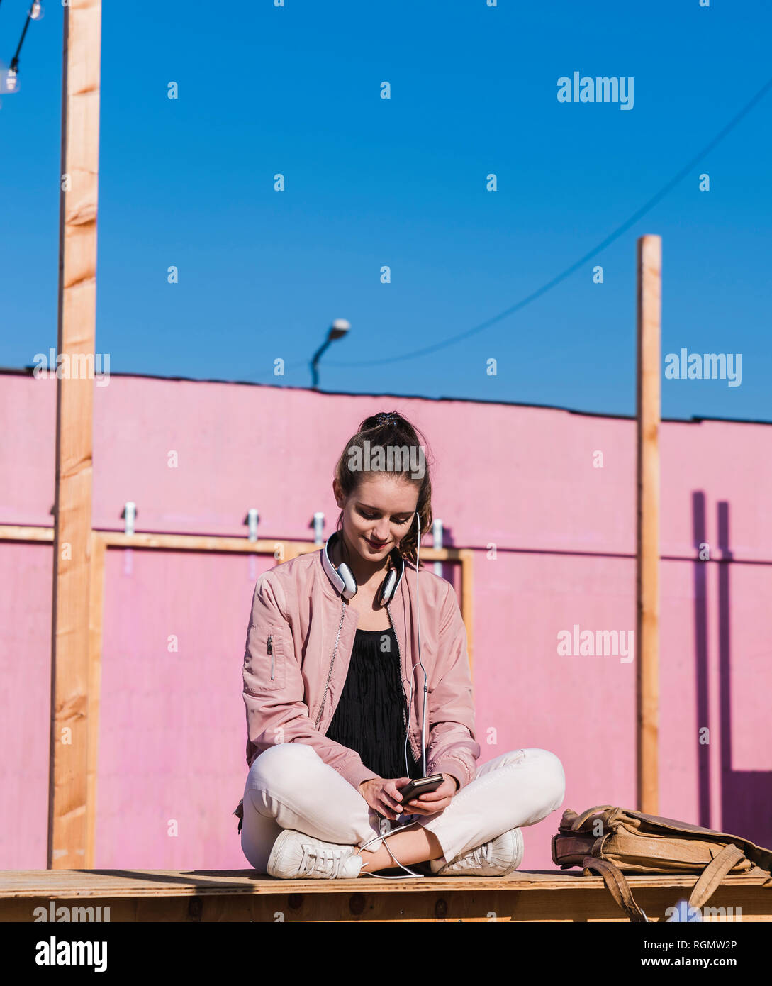 Young woman sitting on platform using cell phone Stock Photo