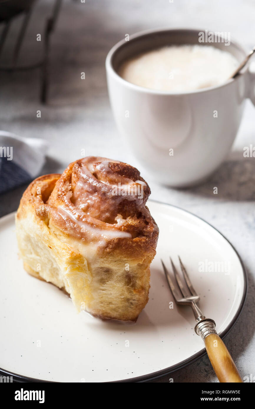 Home-baked cinnamon bun with icing sugar and a cup of coffee Stock Photo