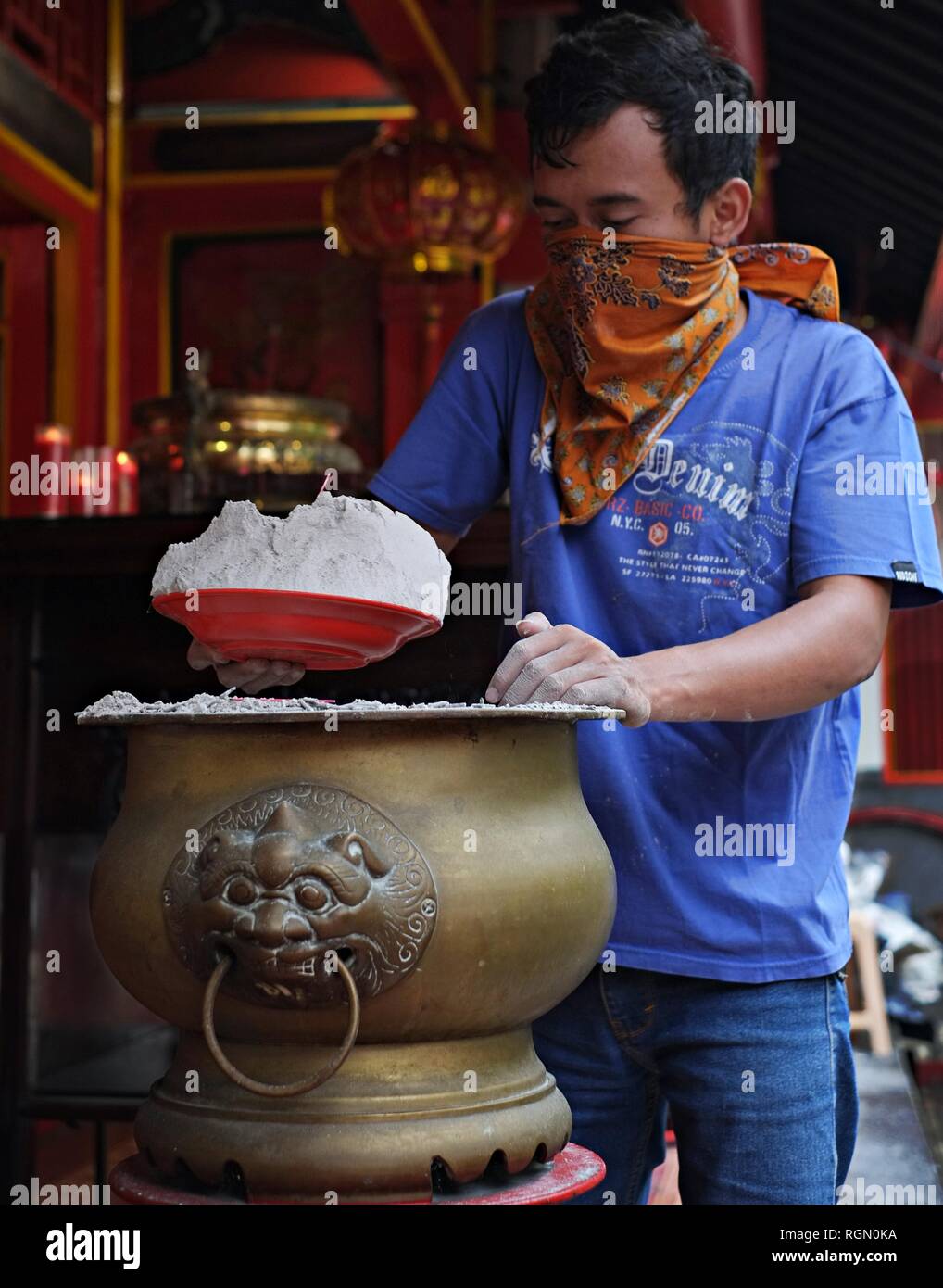 A man is cleaning the incense ashes from a hio-lo in a Buddhist Temple. This yearly tradition before Chinese New Year is called Ayak Abu ritual. Stock Photo