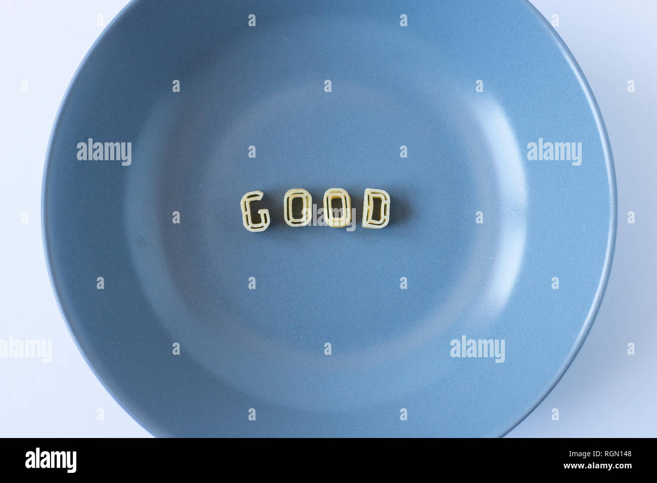 The word "good" composed with real pasta letters in a blue dish. Stock Photo