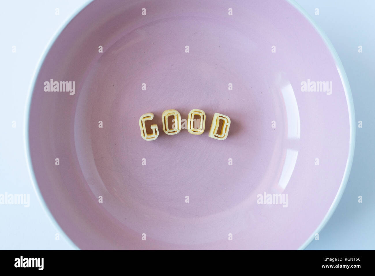 The word "good" composed with real pasta letters in a pink dish. Stock Photo