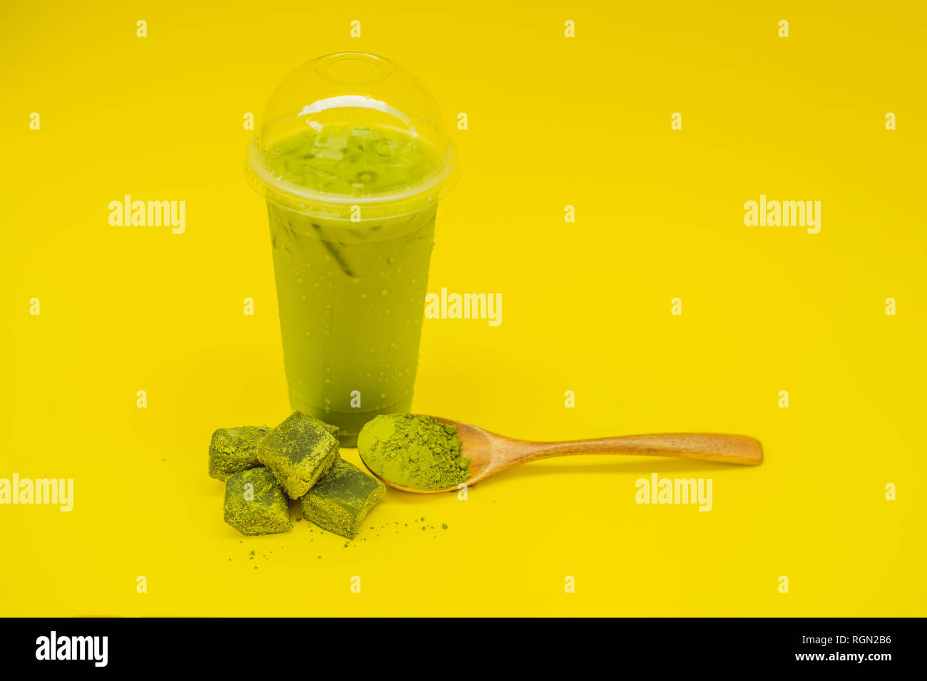 Green tea latte with ice in a plastic cup and straw and spoon with powder  matcha on yellow background. Homemade Iced Matcha Latte Tea with Milk zero  Stock Photo - Alamy