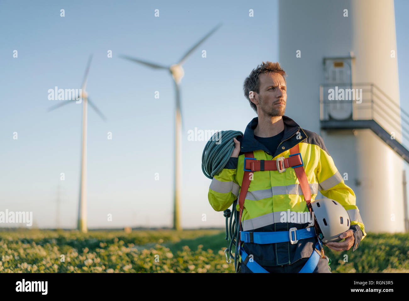 Technician standing at a wind farm with climbing equipment Stock Photo