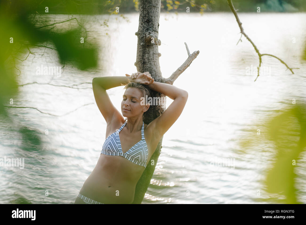 Portrait of girl wearing bikini top leaning against tree