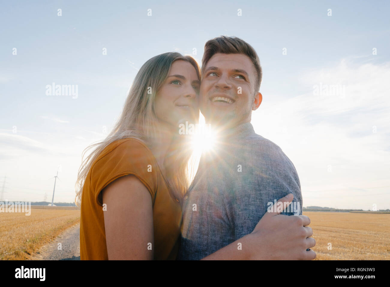 Happy affectionate young couple in backlight in rural landscape Stock Photo