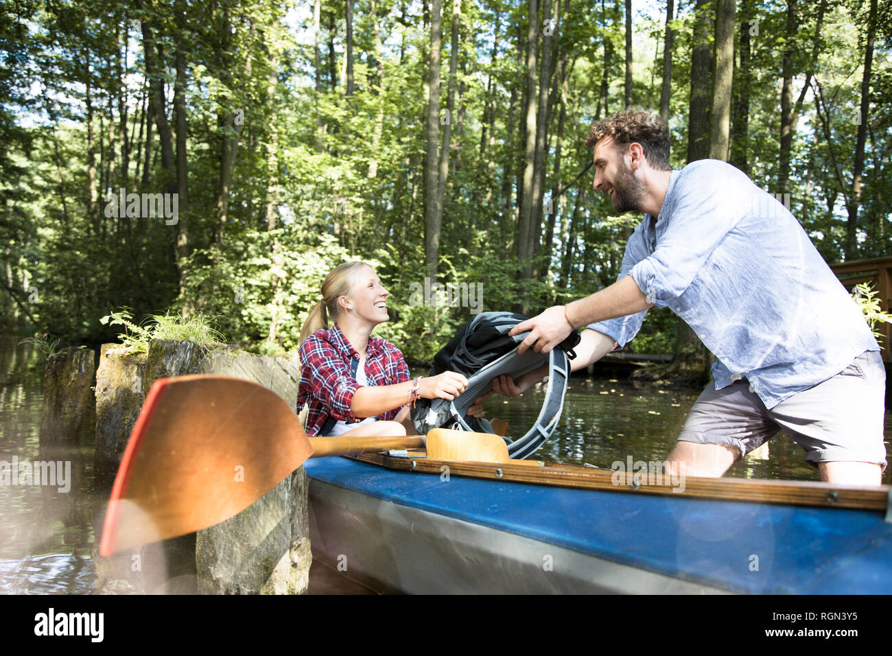 Happy young couple entering canoe in a forest brook Stock Photo