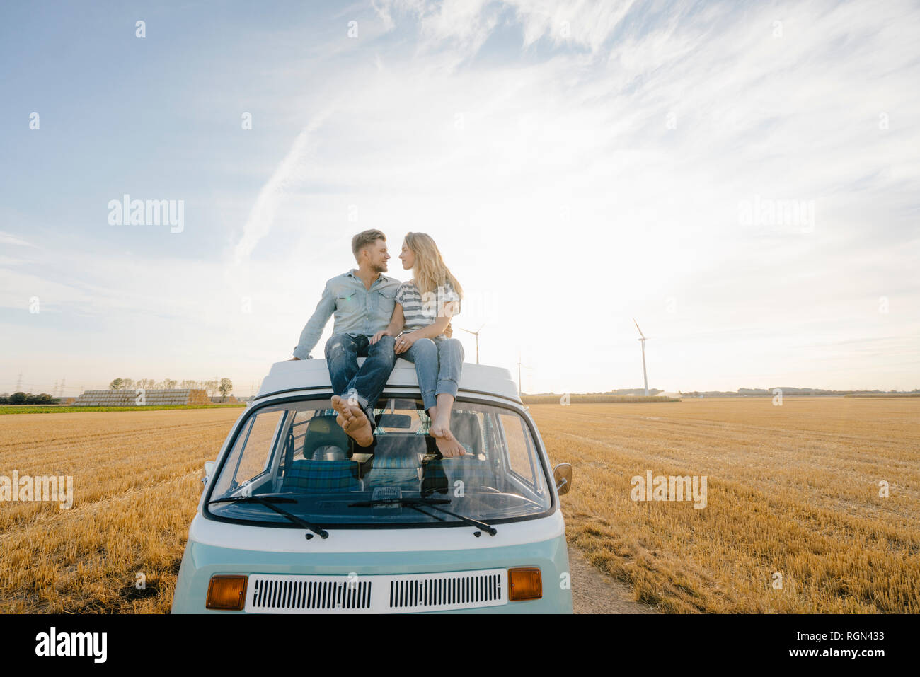 Smiling young couple on roof of a camper van in rural landscape Stock ...