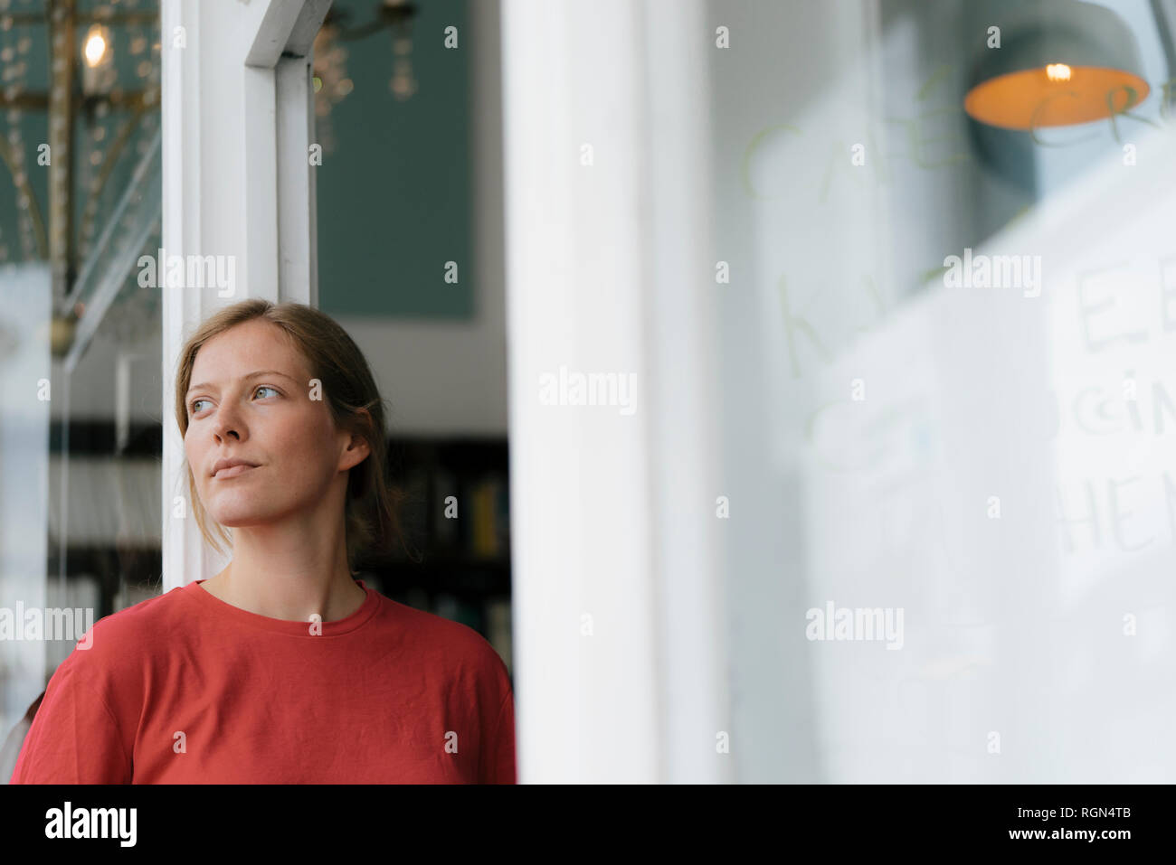 Young woman at French door in a cafe looking around Stock Photo
