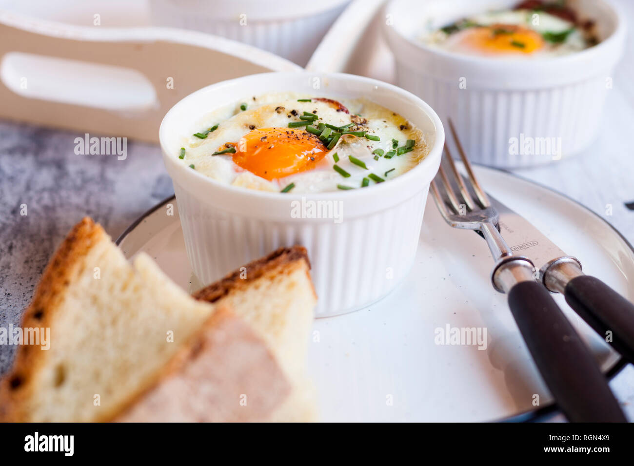 Oefs en cocotte (Individual baked eggs) with spinach, feta, bacon, eggs, and slices of bread Stock Photo