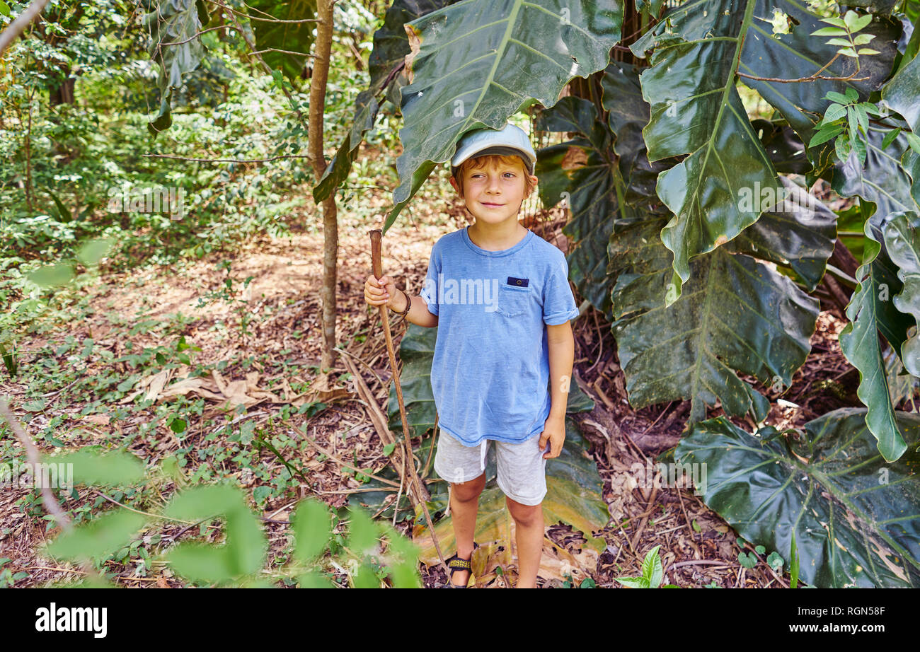 Brazil, Bonito, boy standing in jungle under large leaf Stock Photo