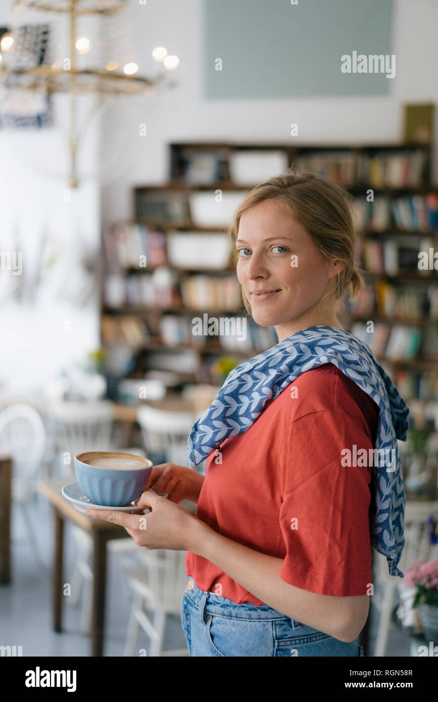 Portrait of smiling young woman serving coffee in a cafe Stock Photo