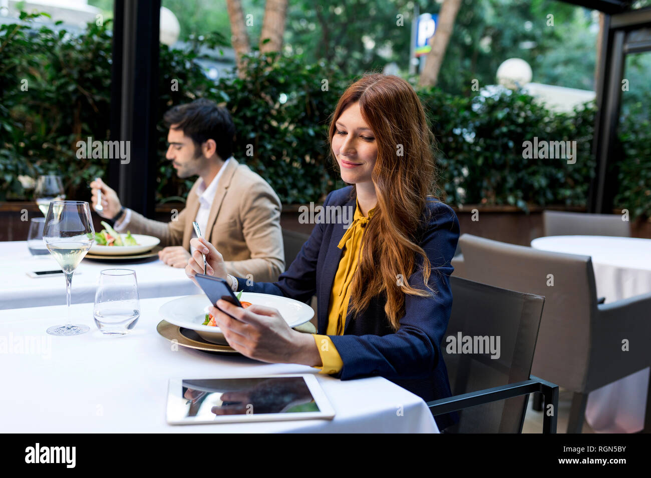 Man eating and woman using cell phone in a restaurant Stock Photo