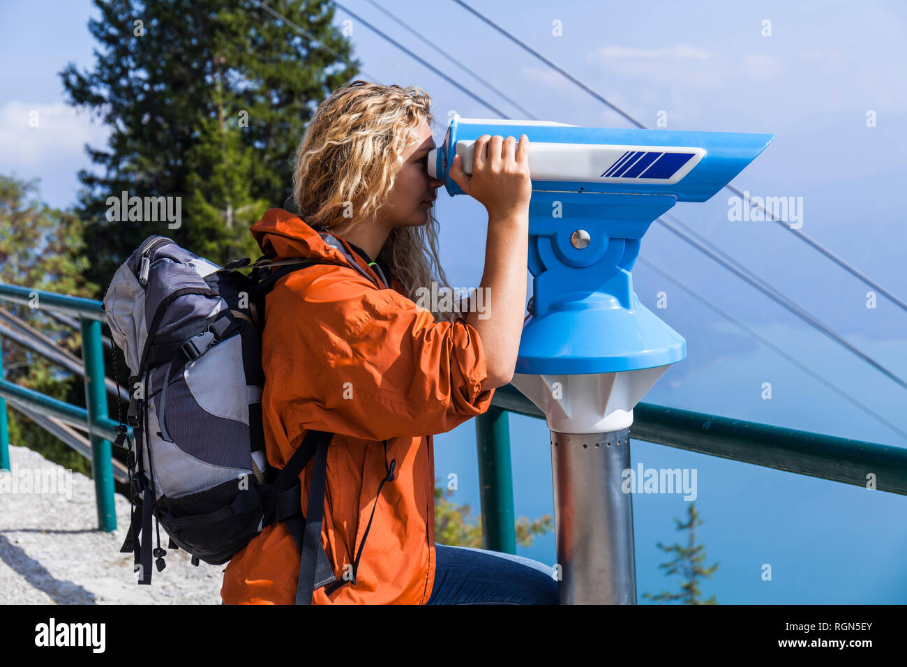 Young woman looking at mountains, using coin operated telescope Stock Photo