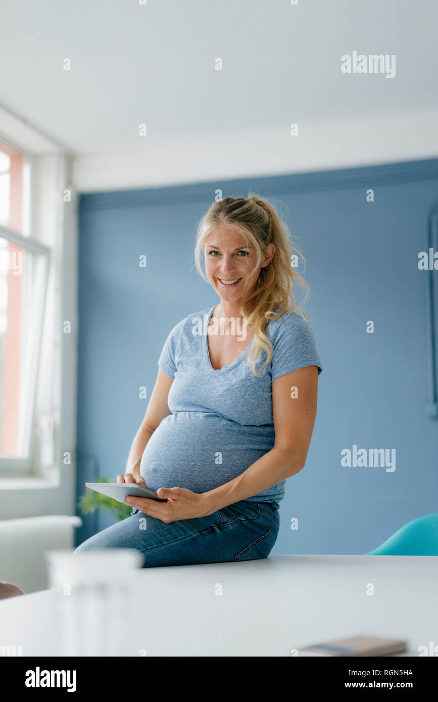 Portrait of smiling pregnant woman holding tablet Stock Photo