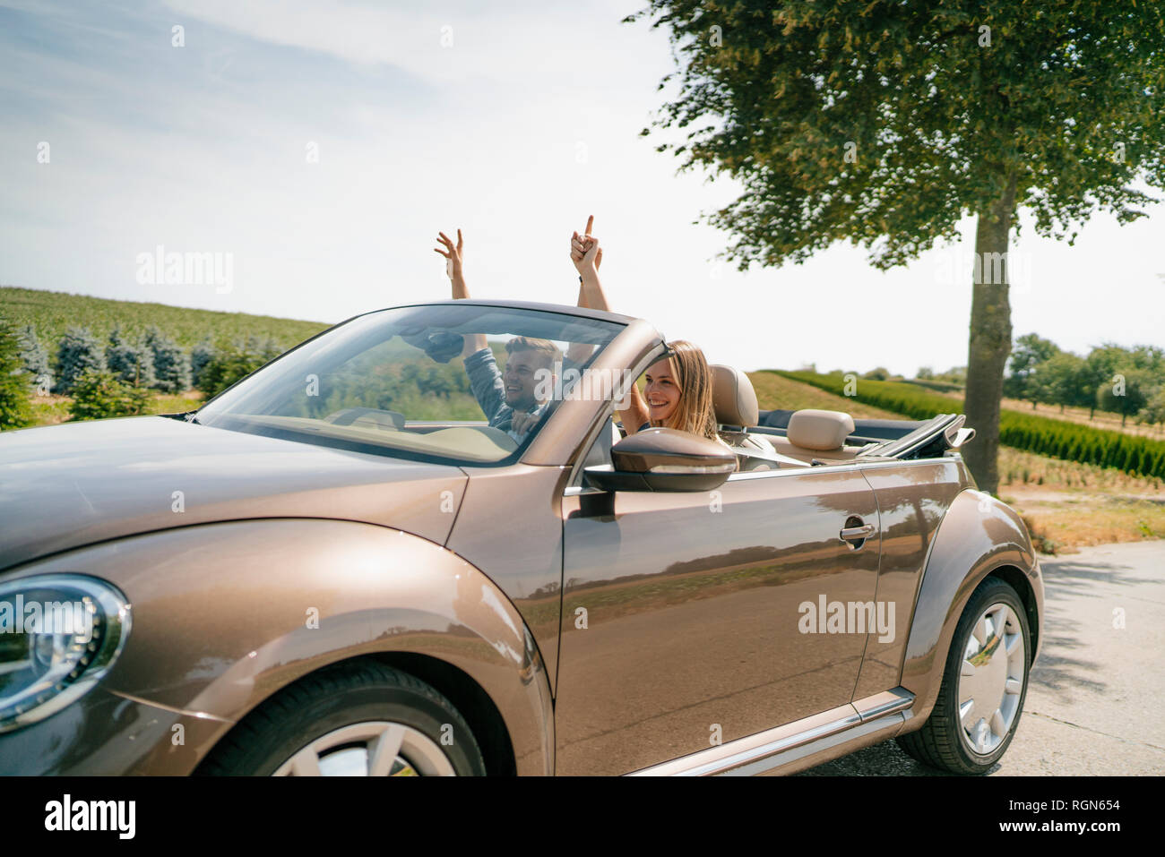 Happy couple driving in convertible car on a country road Stock Photo