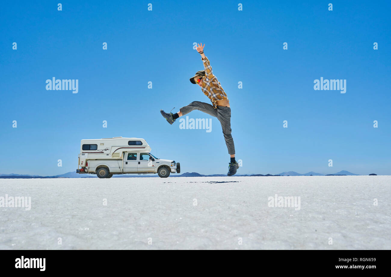 Bolivia, Salar de Uyuni, boy jumping at camper on salt lake Stock Photo