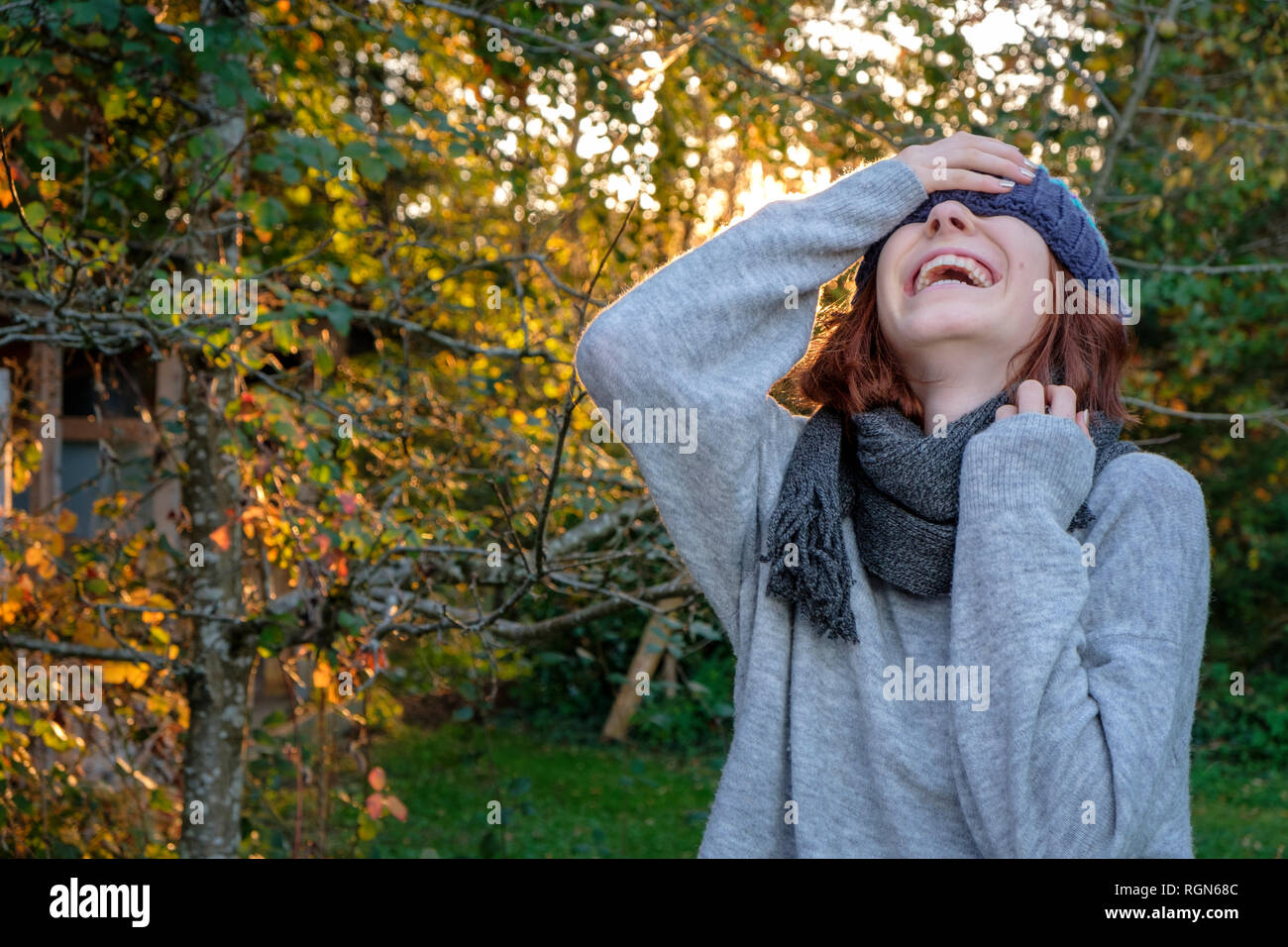 Laughing teenage girl wearing wooly hat and scarf in autumn Stock Photo