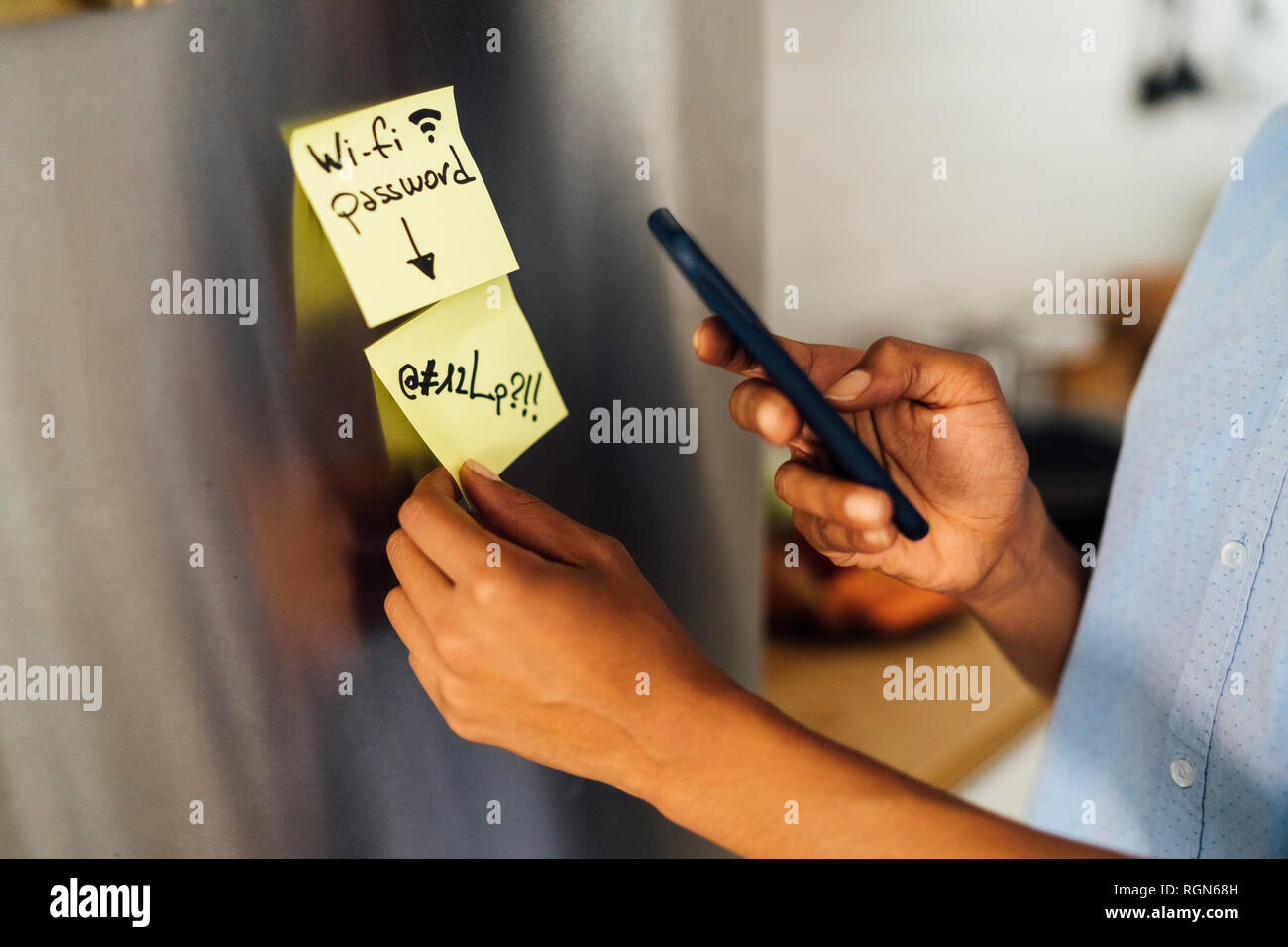 Woman in her kitchen in the morning, posting sticky  notes on the fridge Stock Photo