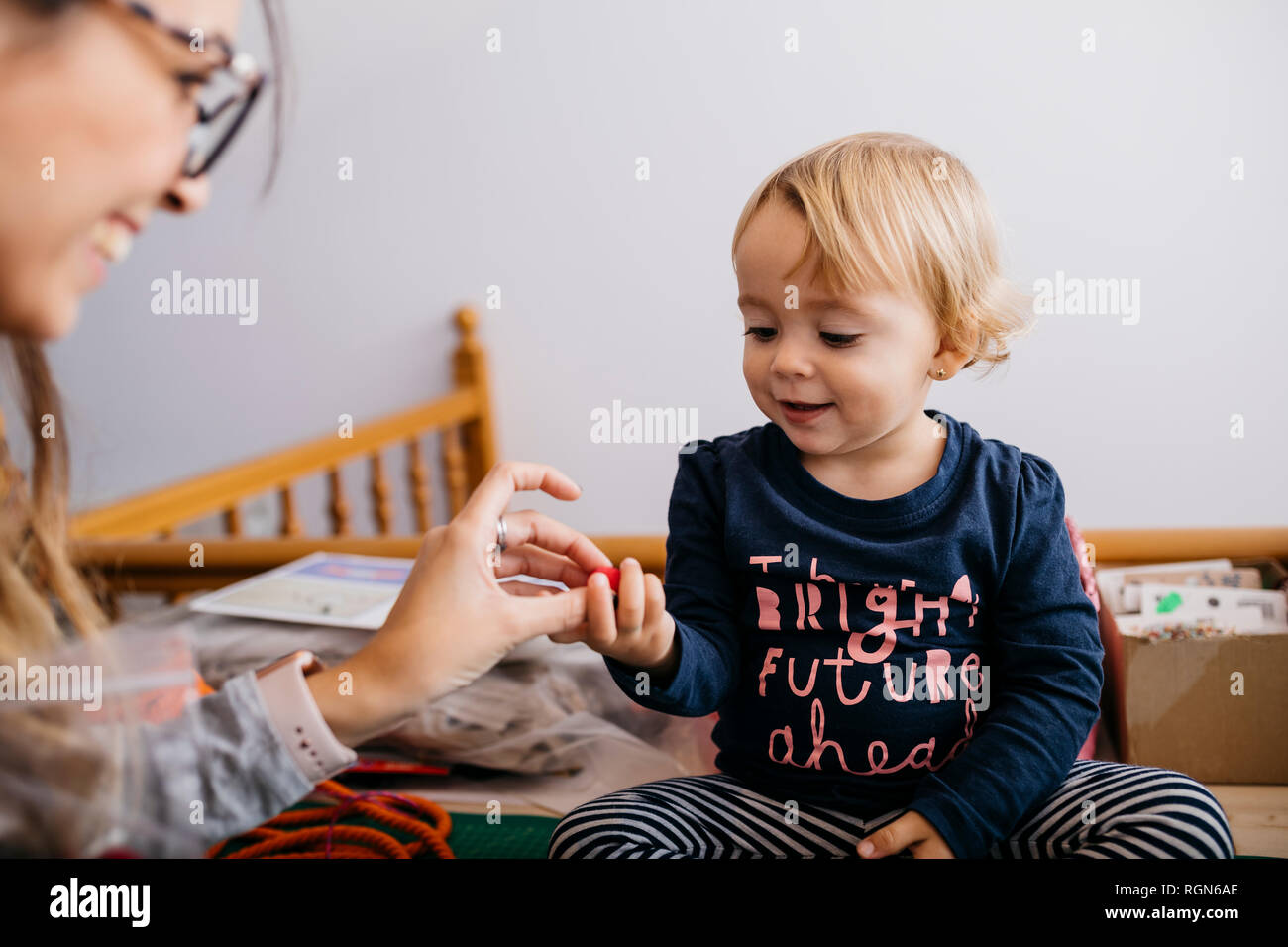Mother giving fashion accessory to little daughter at home Stock Photo