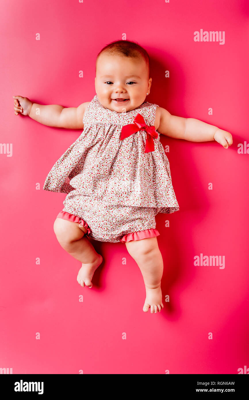 Portrait of happy baby girl lying on pink background Stock Photo - Alamy