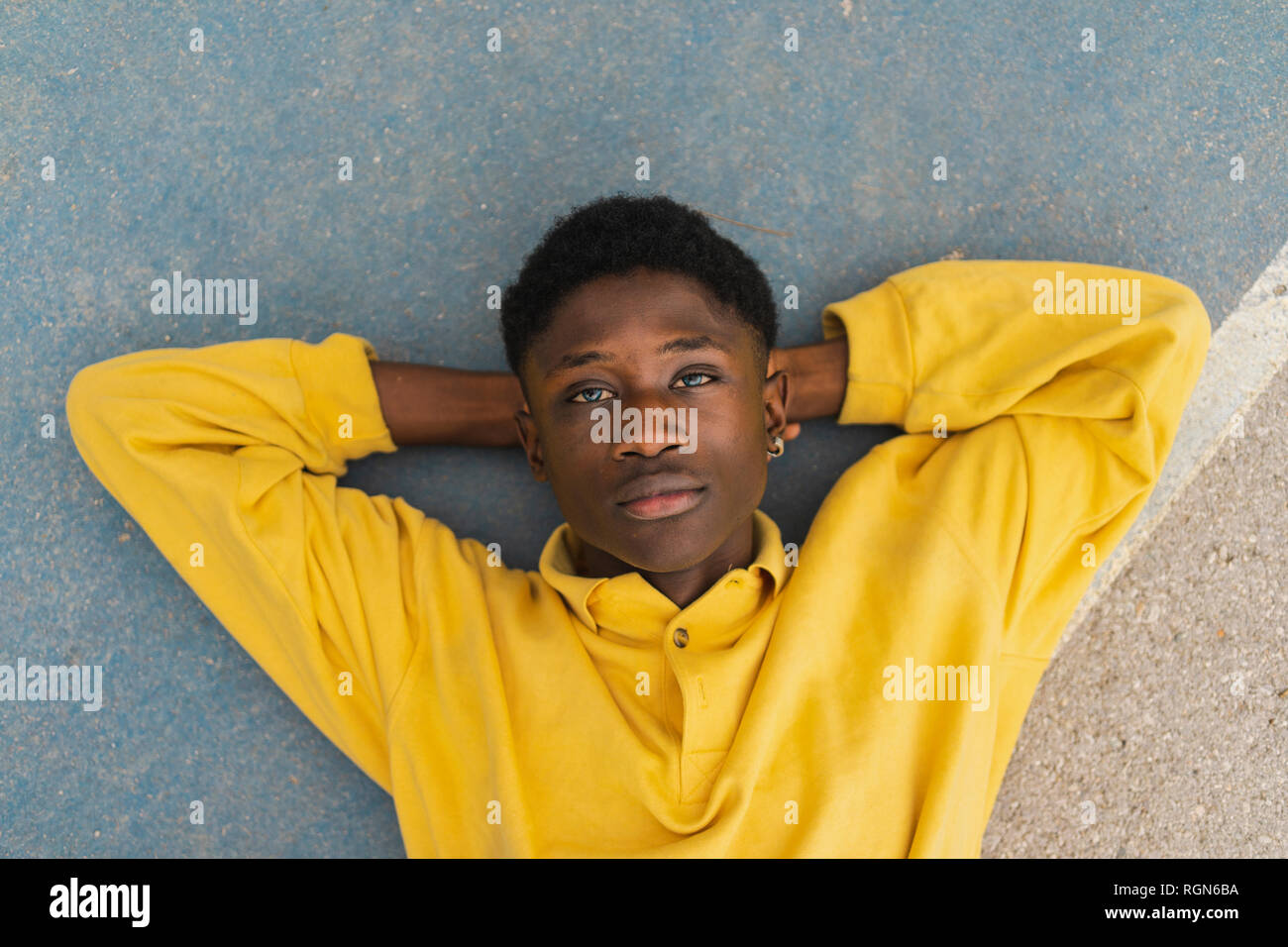 Young black man lying on floor, with hands behind head Stock Photo