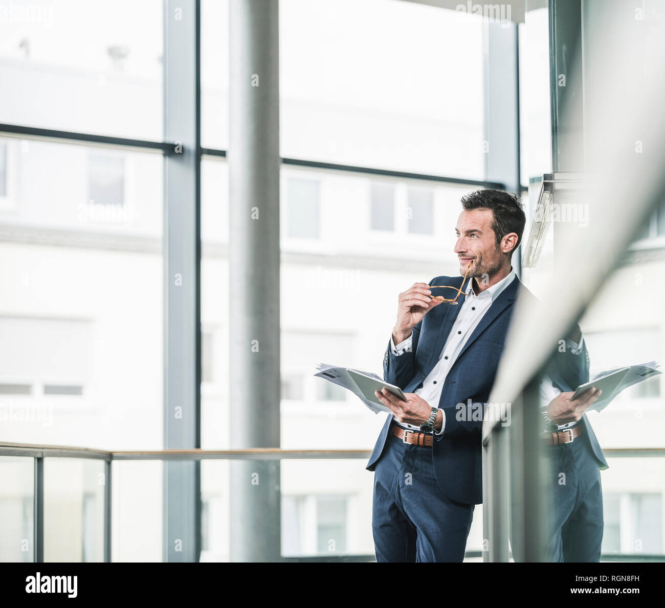Businessman standing in office building, using digital tablet Stock Photo